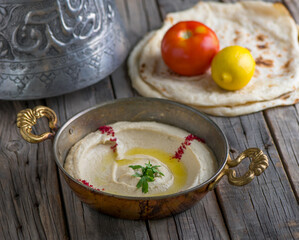 Hommous with pita served in dish side view on wooden table background