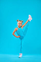 Kid girl doing fitness exercises on pink and pink background in sportswear. Sports concept.