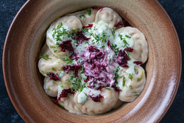 Appetizing dumplings stuffed with potatoes and mushrooms with sour cream, green dill and beetroot
