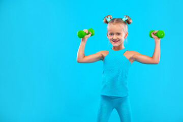Kid girl doing fitness or yoga exercises with dumbbells isolated on blue background