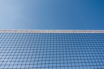 Tennis or volleyball net against clear blue sky background. Outdoors sports field in sunny day. Low...
