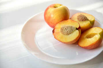 Naklejka na ściany i meble Sliced peaches and nectarines on a white plate