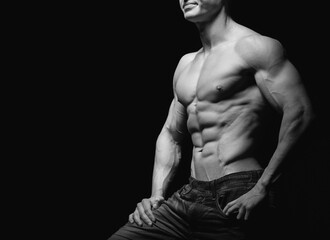 Obraz na płótnie Canvas Fitness concept. Muscular and fit torso of young man having perfect abs, bicep and chest. Male hunk with athletic body on black background