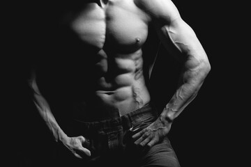 Fototapeta na wymiar Fitness concept. Muscular and fit torso of young man having perfect abs, bicep and chest. Male hunk with athletic body on black background