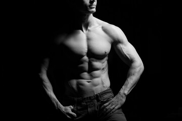 Obraz na płótnie Canvas Fitness concept. Muscular and fit torso of young man having perfect abs, bicep and chest. Male hunk with athletic body on black background