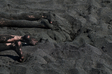 Feet in the black magnetic sand of the Black Sea beach. beautiful black background texture close up. 
