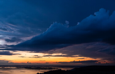 Dramatic sunset sky over Volga river, blue clouds hang over water