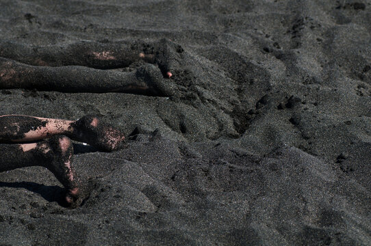 Feet In The Black Magnetic Sand Of The Black Sea Beach. Beautiful Black Background Texture Close Up. 
