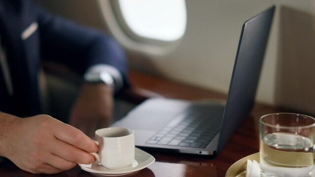 Relaxed businessman working computer on trip. Closeup hand putting coffee cup