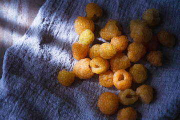 Yellow raspberry on blue cloth, extreme close up, top view.