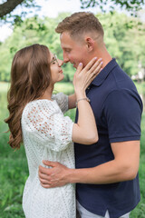 Close up portrait of beautiful woman with dark hair in eyeglasses smiling and trying to kiss her boyfriend in park