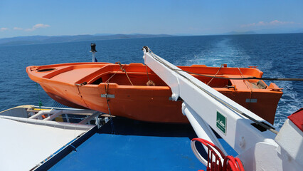 Orange rescue boat on a passenger ship cruising in the Aegean Sea in Greece. Concept photo for safe...