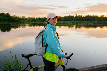 Nice woman riding mountain bike during sunset on the coastline above the lake. Bike travel tourism woman. Summer travel vacation recreation. - 512433384
