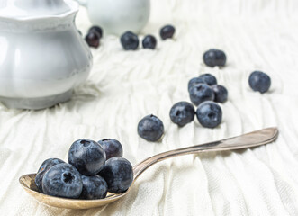 Ripe blueberries with an iron spoon on a white cloth