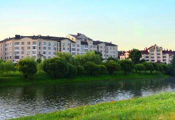River on sunrise. Townhouses buildings and multi-floor home at waterfront. Morning on River in city. Suburb houses and residential building near river in Minsk. House in nature on shore on sunset..