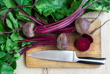 Fresh young beets with juicy tops on a wooden tray