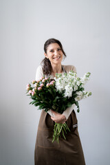 WOMAN florist EMBRACING a bunch of white and pink flowers on white background indoors