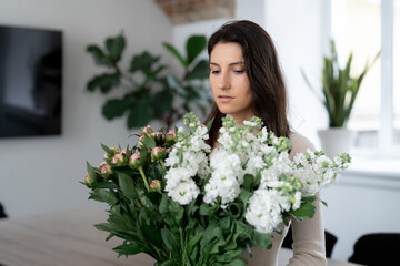 Positive woman holding a huge bouquet of flowers in her office. Birthday present smile.