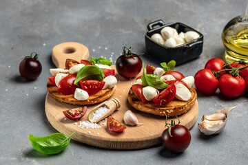 Caprese toasts with mozzarella, cherry tomatoes and fresh garden basil. Traditional italian appetizer or snack, antipasto. banner, menu, recipe place for text, top view