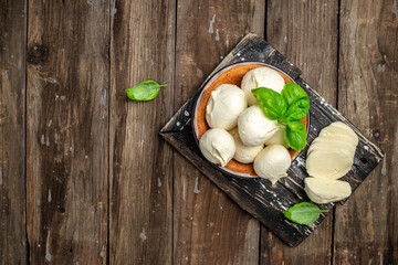 Traditional mozzarella cheese with fresh basil leaves on a dark wooden background. banner, menu,...