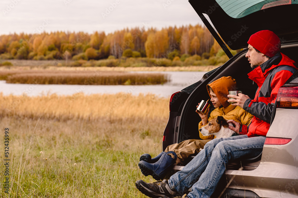 Wall mural family traveling by car having rest and looking at beautiful fall landscape