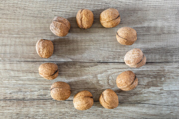 Lined circle of whole walnuts on brown wood textured background, copy space