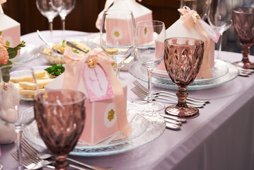 Gift boxes on a plate for guests on a served table for a holiday decorated with rose flowers