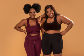 Active two plus size femal friends posing after training in fashionable sporty clothes ,smiling. Body acceptance.