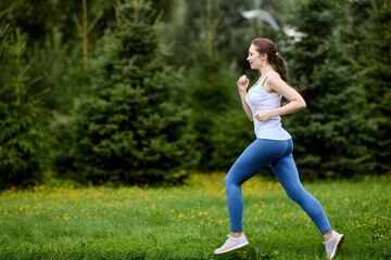 Young female runner trains in forested area.