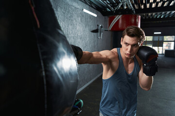 Serious focused sportsperson practicing punches at gym