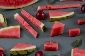 Beautiful pattern with fresh watermelon slice and cherries on green background.