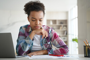 Focused biracial student girl studying preparing for exam doing homework at home. Distance education