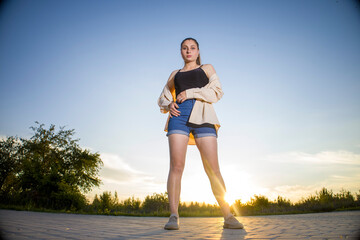 Girl in shorts and a shirt on a background of clear sky.