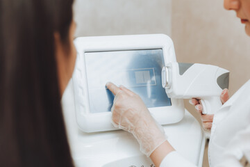 The beautician's hand presses the buttons on the device for laser hair removal. Close-up.Skin care...