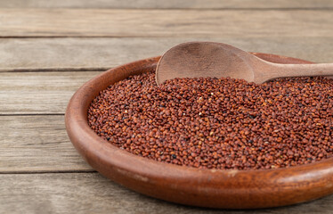 Narrow focus, raw red quinoa in a plate over wooden table