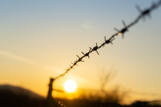 Barbed wire on the fence during sunset colorful sky. Slovakia	