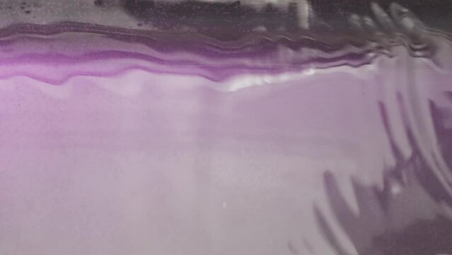 Purple iridescent water . Action . A pond with shiny slightly pink water that shimmers in the sun.