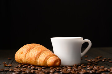 Croissants with coffee and coffee beans on a wooden background.