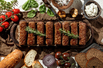 Grilled meat at wooden plate with herbs and fresh vegetables. Sunny day, barbeque. Indgridients on a table, top view