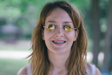 young woman with yellow round glasses and tooth braces
