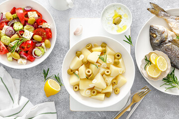 Boiled potatoes with garlic and olives, fresh vegetable greek salad, baked dorada fish sea bream and tzatziki dip. Healthy food. Mediterranean diet