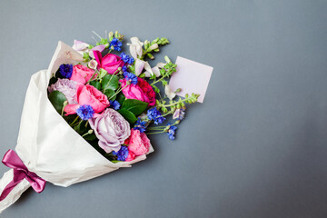 Fresh bouquet of roses foxgloves bachelor buttons flowers wrapped in paper and arranged on...