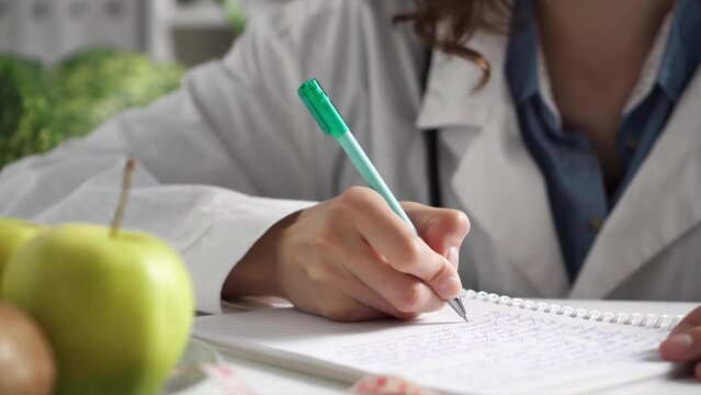 a woman doctor writes down the patient's medical history, the doctor writes in a notebook writing a prescription to the patient consultation receiving a patient for prescribing treatment
