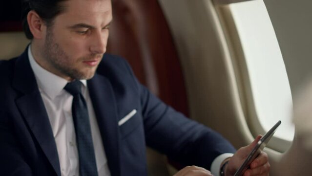 Confident leader using tablet on airplane trip. Closeup man hands touch screen