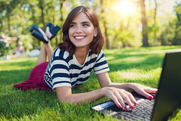 woman with laptop in the park at hat with cap