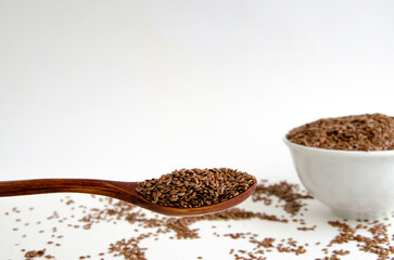 white flax seed on a wooden spoon in a distant plate of flax