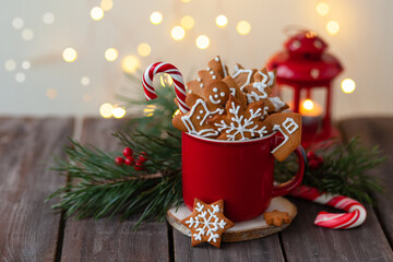 Christmas composition with gingerbread cookies, candy cane and marshmallow in a red mug. Cozy home atmosphere, delicious sweet holiday dessert. Traditional spices: cinnamon, anise, cardamom