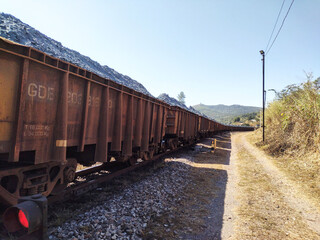 Train cars loaded with ore with side road at Itabira Minas Gerais Brazil and clean sky background