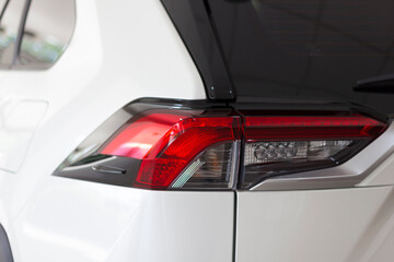 The back of a white expensive crossover car: Close up detail on one of the LED red tail light modern crossover car. Exterior detail automobile. Mock up for the advertising industry.