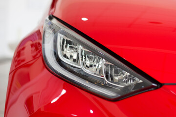 Headlights of a red modern car close up.